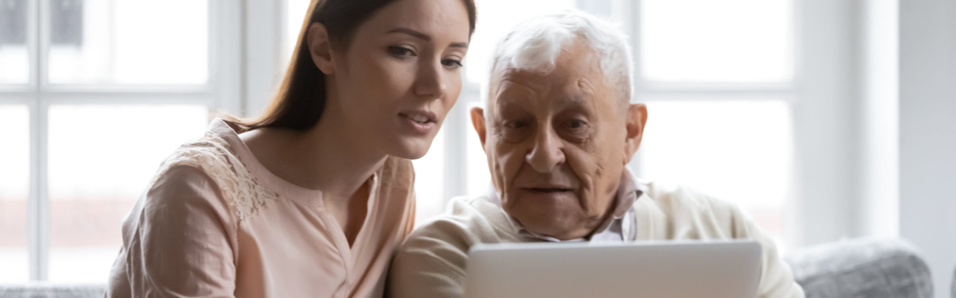 Young woman and senior man looking at laptop